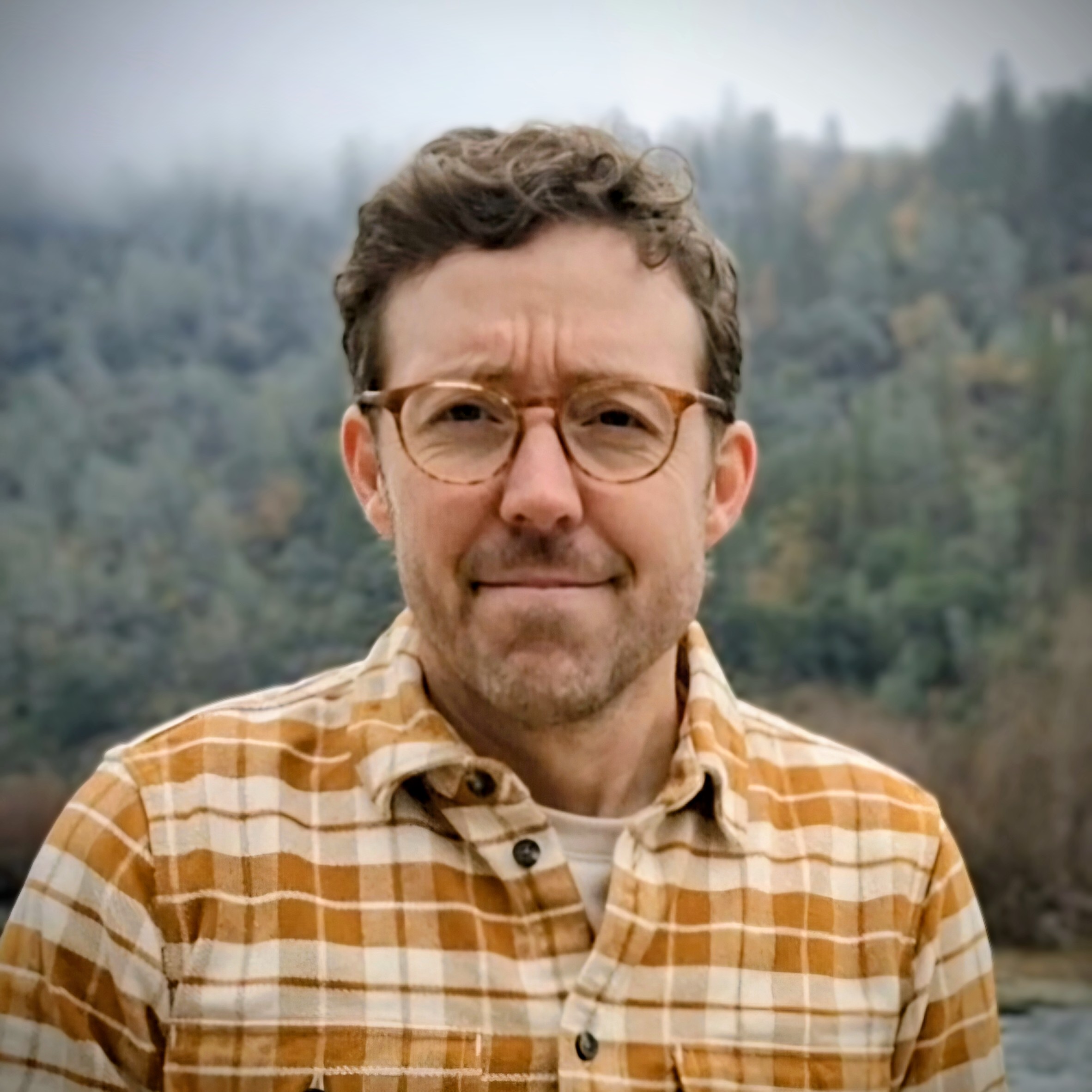 A profile picture of a person with a natural background.